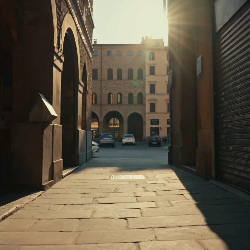 Sunlit cobblestone alley opening onto a historic European square at golden hour — editorial fashion backdrop